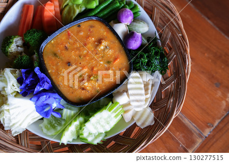 A hand is dipping Chili paste with fresh vegetables, asain cuisine 130277515