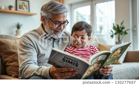 Grandfather reading a book to his grandchild in a bright living room, both smiling. Grandfather reading a book to his grandchild in a bright living room, both smiling. 130277687