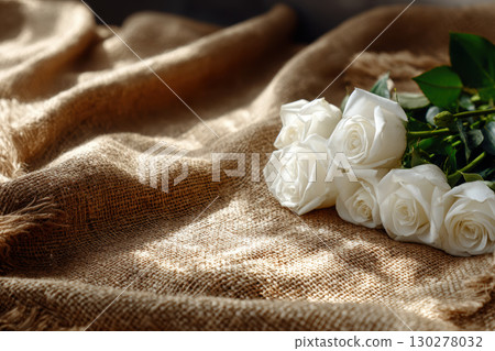 Freshly cut white roses on rustic burlap in natural light 130278032