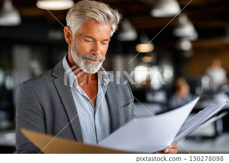 Professional economist analyzes reports in minimalist office 130278098