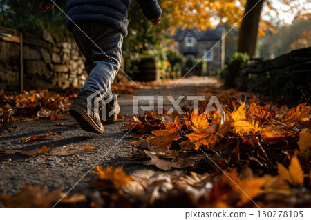 Child playing in colorful autumn leaves on a park path 130278105