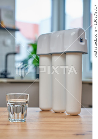 Water filter system and glass of clean water on kitchen table Water filter system and glass of clean water on kitchen table 130278317