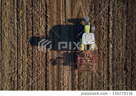 Tractor working on agricultural field, plowed farmland 130278336