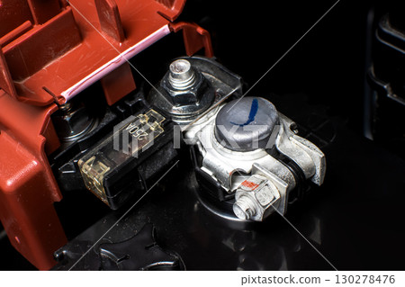 Close-up of a car battery positive terminal in red with fuse and connector 130278476