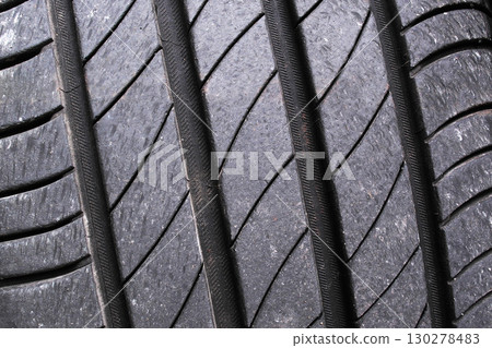 Close up of worn car tire tread showing rubber texture and grooves Close up of worn car tire tread showing rubber texture and grooves 130278483