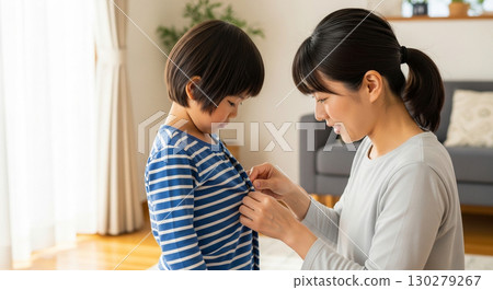 一位母親正在幫孩子扣衣服釦子 130279267