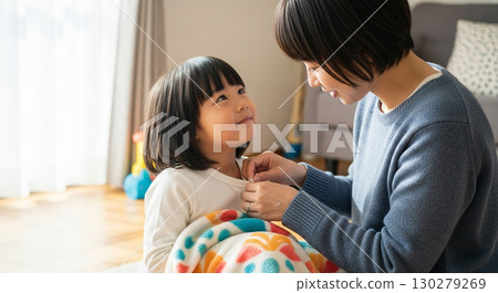 一位母親正在幫孩子扣衣服釦子 130279269