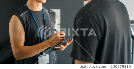 A male trainer giving individual instruction to members at a personal gym 130279510