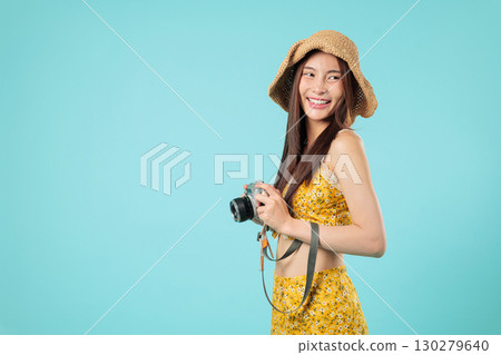 Happy young Asian woman travel tourist, cheerful with camera, vacation aside, looking in sunhat, a happy tourist smiling on holiday lifestyle, headshots isolated studio blue background 130279640