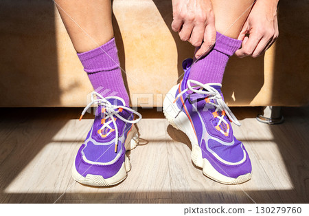 Woman adjusts her purple socks after putting sneakers. Woman adjusts her purple socks after putting sneakers. 130279760