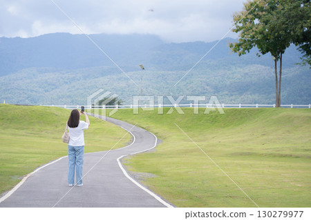 Relax and wellness concept with woman walk on road in garden and mountain background at chiangmai thailand in raining season 130279977