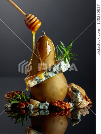 Blue cheese with honey, pear, walnuts, and rosemary on a black background. 130280037