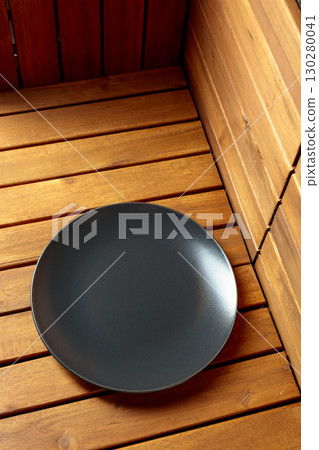 Empty black plate on natural wooden background. 130280041