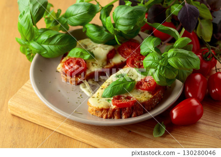 Hot open sandwiches with mozzarella, tomatoes and basil. 130280046