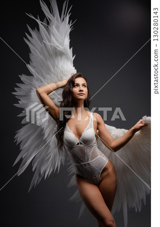 Woman poses gracefully with wings illuminated by soft projective lighting Woman poses gracefully with wings illuminated by soft projective lighting 130280143