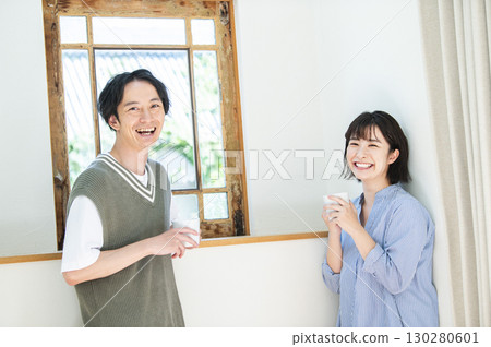 一對年輕夫婦喝著咖啡看著相機 一對年輕夫婦喝著咖啡看著相機 130280601