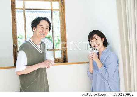 一對年輕夫婦喝著咖啡看著相機 一對年輕夫婦喝著咖啡看著相機 130280602