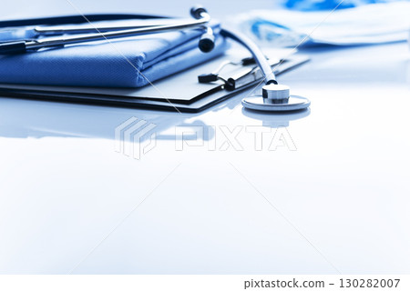 Healthcare medical background with copy-space of stethoscope clipboard and folded overalls on table 130282007