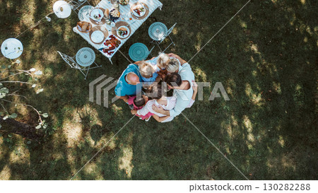 Drone shot of grandparents, parents and children hugging in circle at family celebration Drone shot of grandparents, parents and children hugging in circle at family celebration 130282288