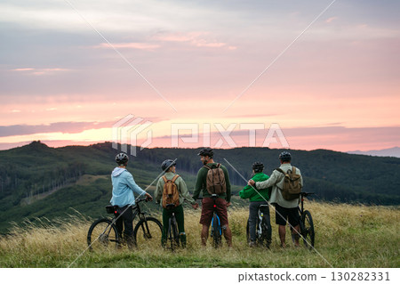 Family standing with bicycles at sunset in mountains. Cycling trip during autumn day. 130282331