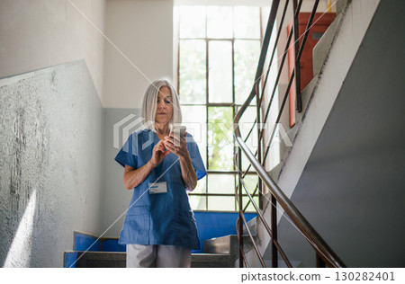 Tired nurse taking break during hospital shift, texting with family. Tired nurse taking break during hospital shift, texting with family. 130282401