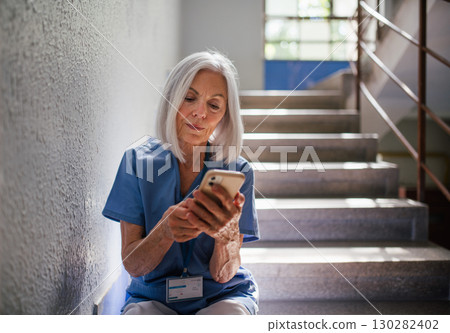 Tired nurse taking break during hospital shift, texting with family. 130282402