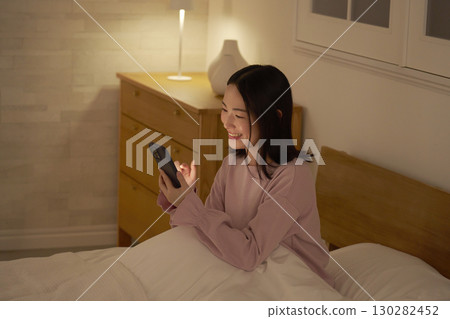 A woman using a smartphone in bed A woman using a smartphone in bed 130282452