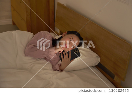 A woman using a smartphone in bed 130282455