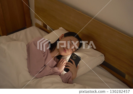 一名女子在床上玩智慧型手機時睡著了 130282457