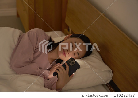 A woman falls asleep while using her smartphone in bed 130282458