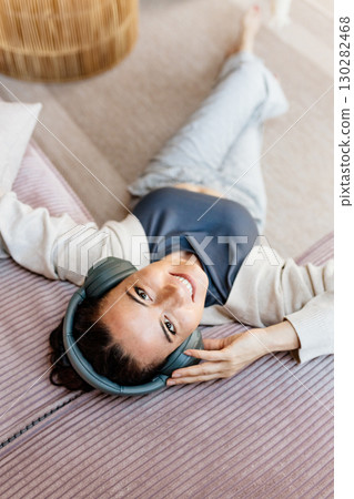 Woman relaxing at home, enjoying music after work. Woman relaxing at home, enjoying music after work. 130282468