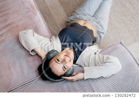 Woman relaxing at home, enjoying music after work. 130282472
