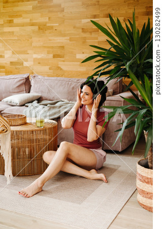 Woman relaxing at home with hair rollers and headphones 130282499