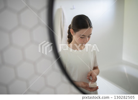 Teenager treating acne, taking care of her skin at home. Teenager treating acne, taking care of her skin at home. 130282505