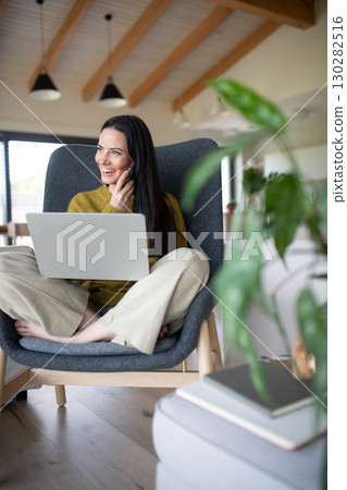 Female freelancer working from home, making phone call with client. 130282516