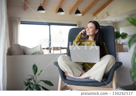 Female freelancer working from home, making phone call with client. 130282517