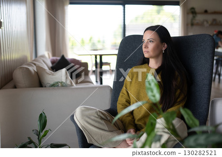 Depressed woman sitting in armchair and staaring at nothing. 130282521