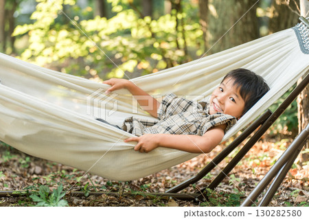 兒童、小學生、男孩在露營地的吊床上玩耍(戶外、旅行、休閒、野餐) 兒童、小學生、男孩在露營地的吊床上玩耍(戶外、旅行、休閒、野餐) 130282580