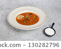 Rich soup with smoked meats, sausages, lemon, and olives on a gray background 130282796