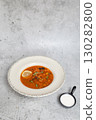 Rich soup with smoked meats, sausages, lemon, and olives on a gray background 130282800