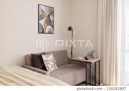 A Stylish and Modern Living Space Featuring a Cozy Sofa Alongside Beautiful Artwork 130282907