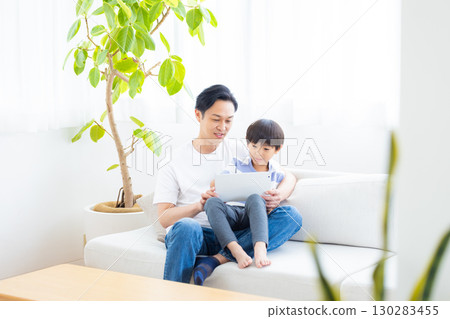 Family tablet dad and son relaxing on sofa 130283455