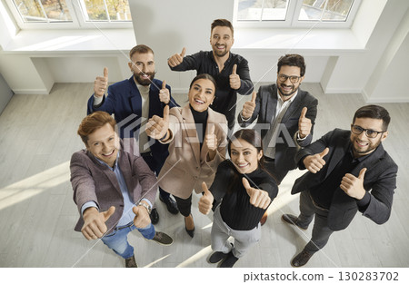 Team of happy, smiling business men and women standing in office, looking up and showing thumbs up Team of happy, smiling business men and women standing in office, looking up and showing thumbs up 130283702