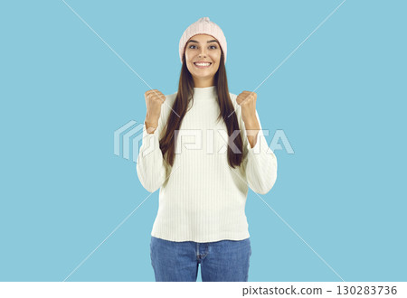 Portrait of happy beautiful young woman in winter clothes smiling and doing yes gesture 130283736