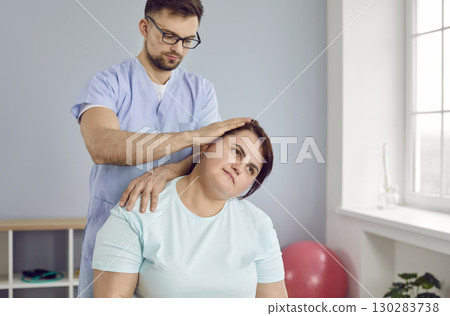 Young professional physiotherapist preparing fat woman patient for gym sport exercises. 130283738
