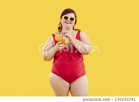 Fat woman in red swimsuit and sunglasses holding cocktail isolated on yellow background. Fat woman in red swimsuit and sunglasses holding cocktail isolated on yellow background. 130283741
