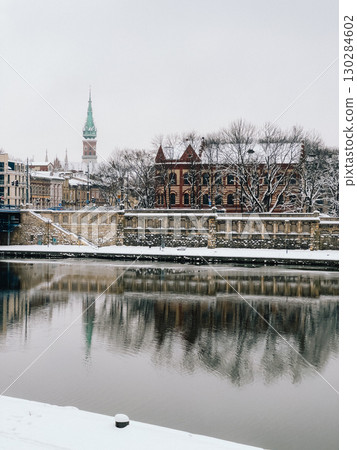 Panoramic view of Krakow reflecting on Vistula river during snowy winter day, featuring characteristic tower of St. Joseph's Church. Snowy panorama capturing historic Krakow cityscape, Vistula river 130284602