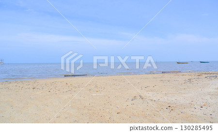 Sandy Beach with Calm Sea and Traditional Fishing Boats under Blue Sky Sandy Beach with Calm Sea and Traditional Fishing Boats under Blue Sky 130285495
