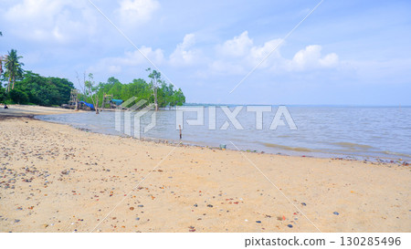 Sandy Beach with Calm Sea and Green Trees on Tropical Coastline 130285496