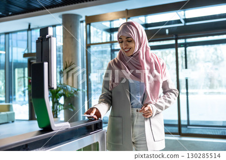 Woman in pink hijab standing in the office at the security control 130285514